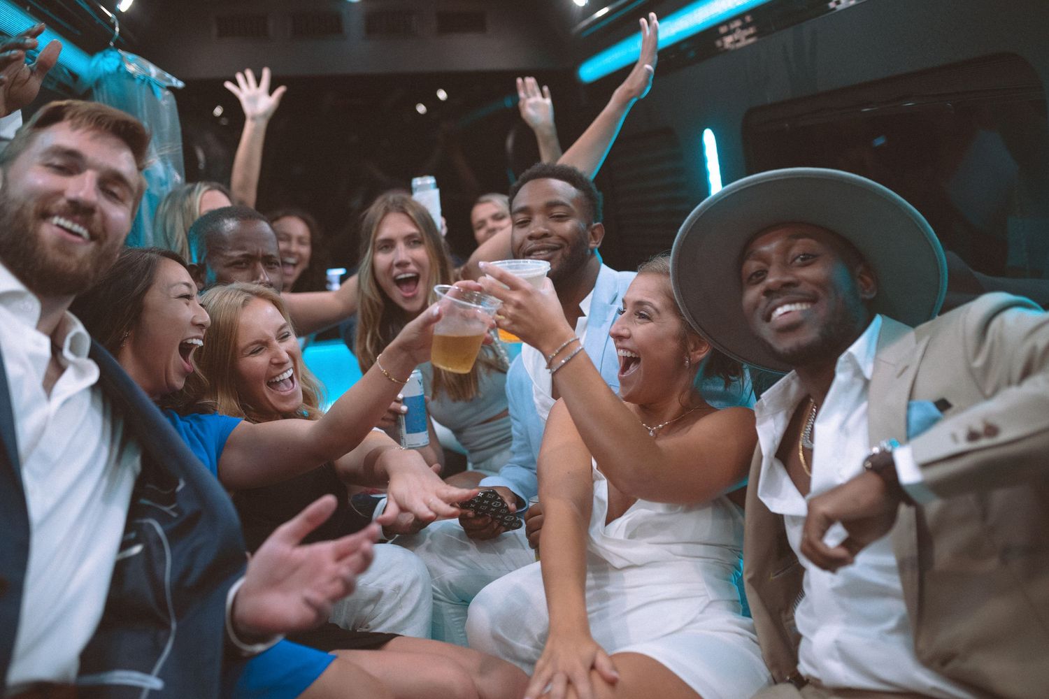 Wedding party celebrates with drinks and cheers inside a party bus after the reception.