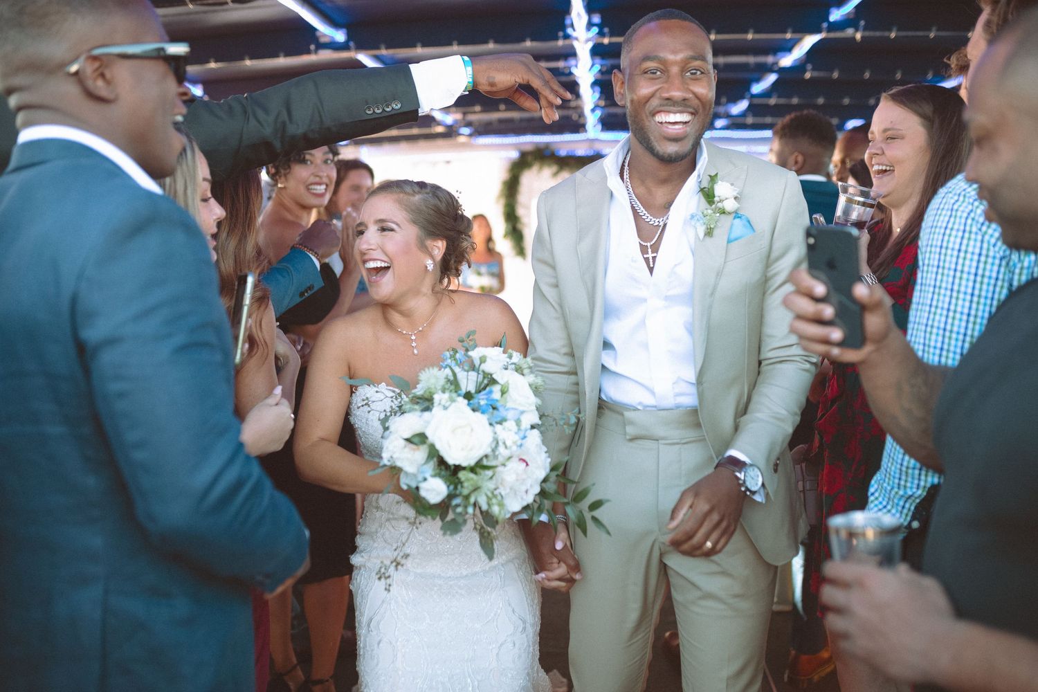 Radiant newlyweds walking joyfully through cheering guests after their wedding ceremony.