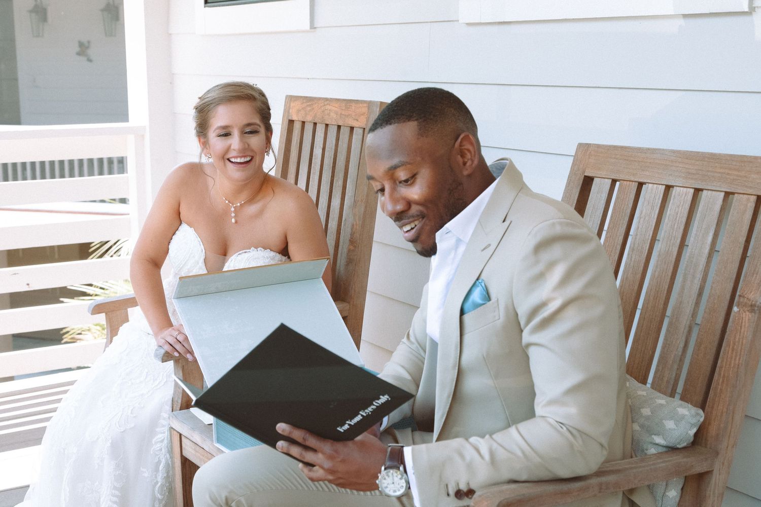 Happy couple in wedding attire sharing a joyful moment while looking through their wedding photo album.