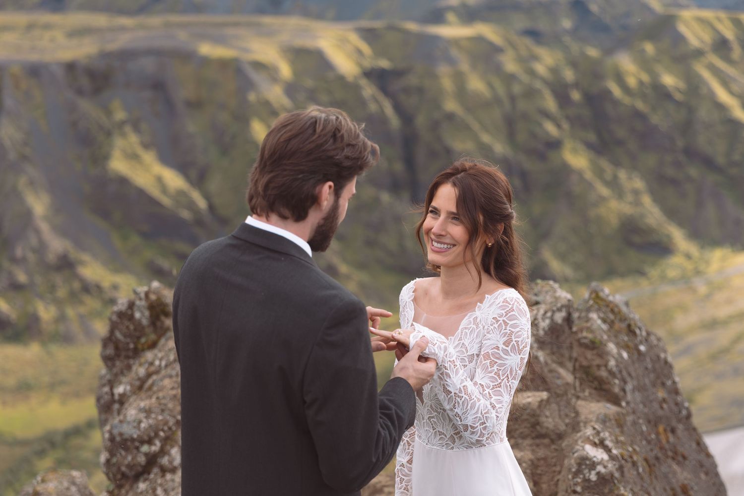 Smiling bride receives wedding ring from groom during intimate outdoor elopement ceremony in Iceland.