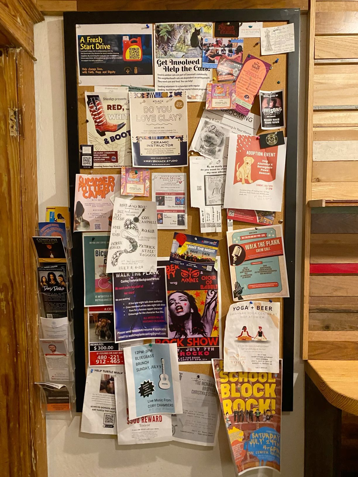 Community bulletin board covered with colorful flyers, brochures, and local event announcements on a wooden wall.