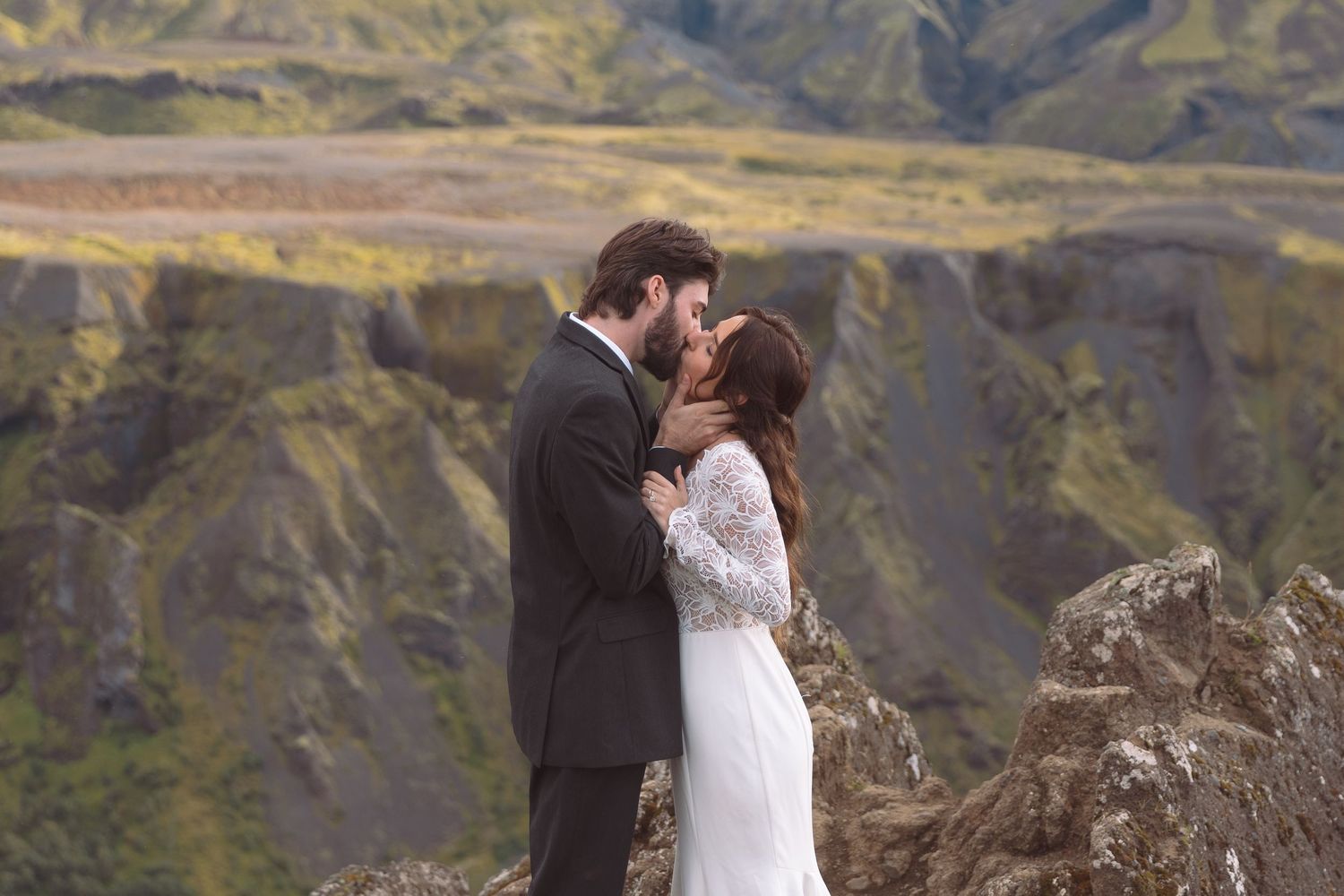 Newlywed couple shares first kiss surrounded by dramatic green volcanic mountains in Iceland elopement.