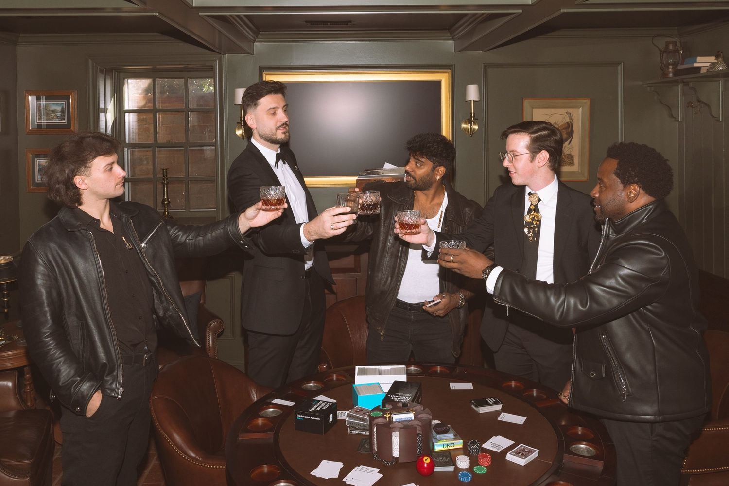 Groom and groomsmen in stylish attire toasting drinks at wedding pre-ceremony celebration.