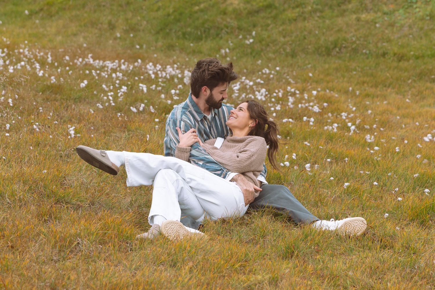 Romantic couple sitting together in a wildflower meadow, sharing a tender moment in the Icelandic countryside.