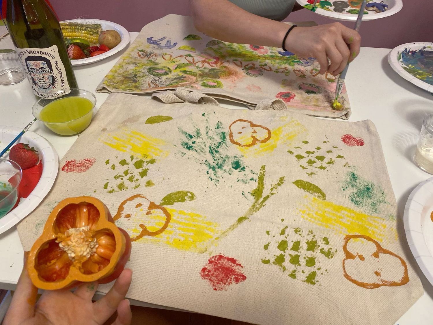 Hands-on vegetable stamp art activity on canvas tote bag with colorful prints using bell peppers and other produce.