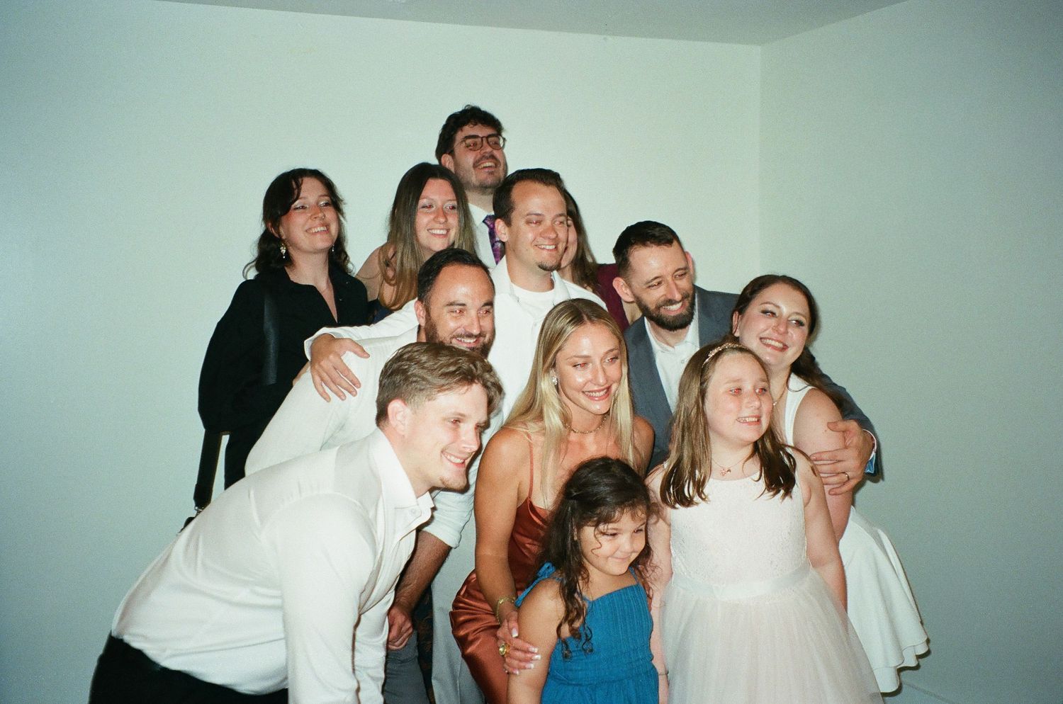 Large group of smiling friends and family posing together for a fun photo at a celebration or wedding event.