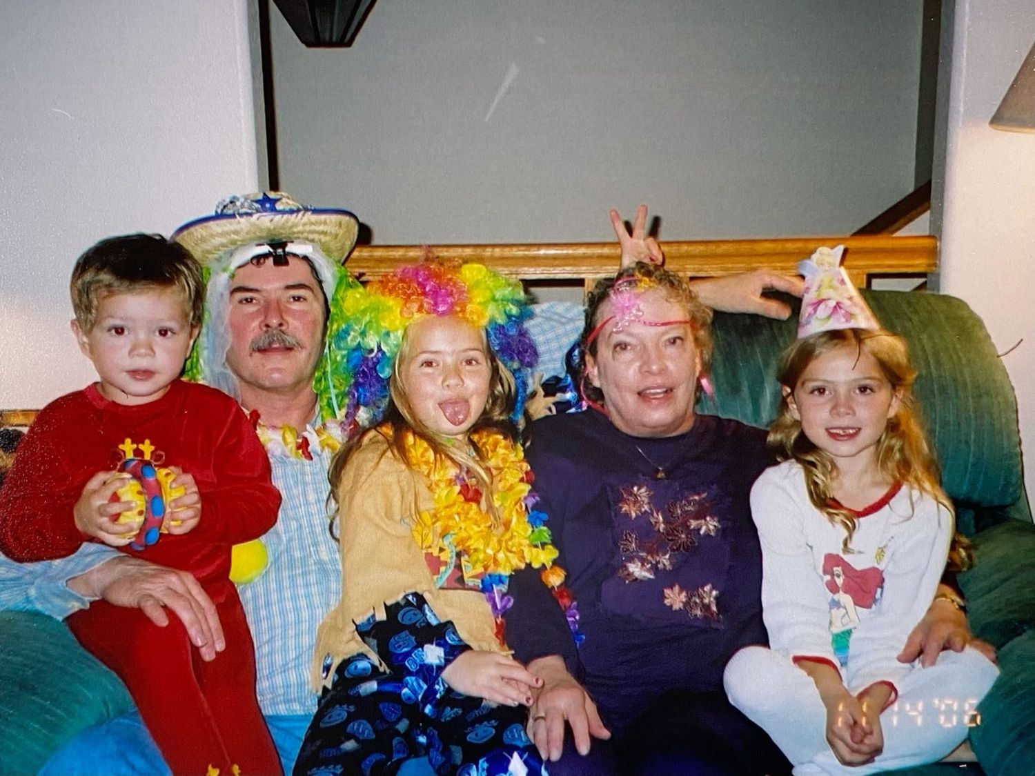 Family portrait with adults and children wearing colorful clown costumes and party hats at a celebration.