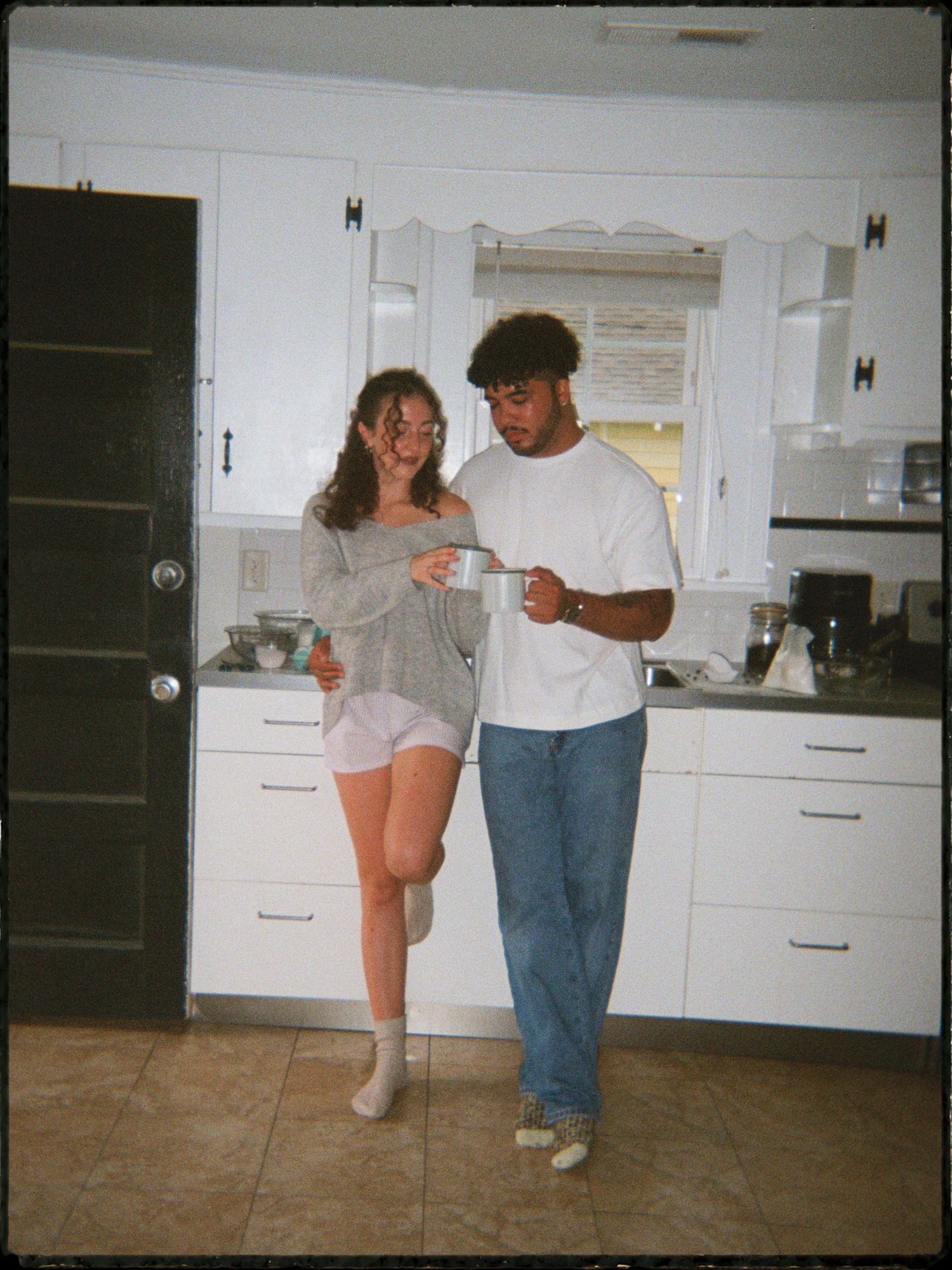 Young couple sharing a casual moment together in a bright white kitchen at home.