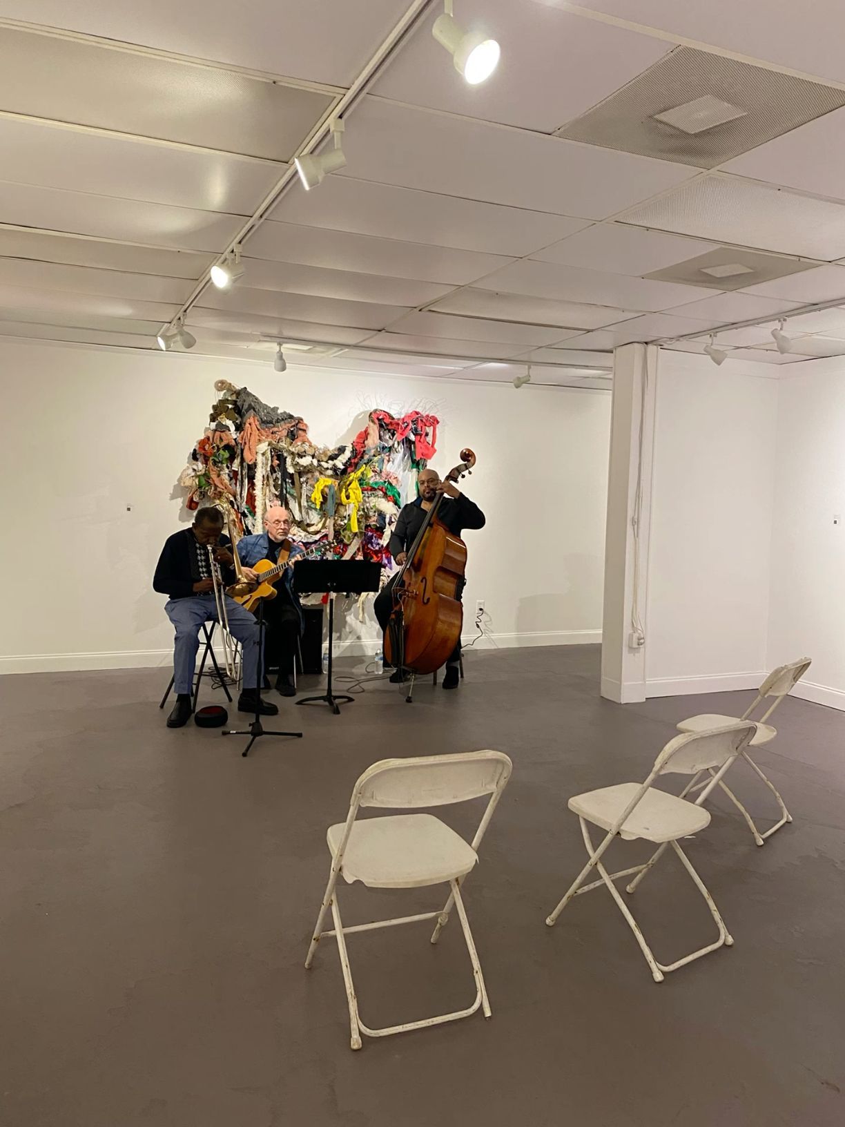 Two musicians playing guitar and double bass in a white art gallery space.