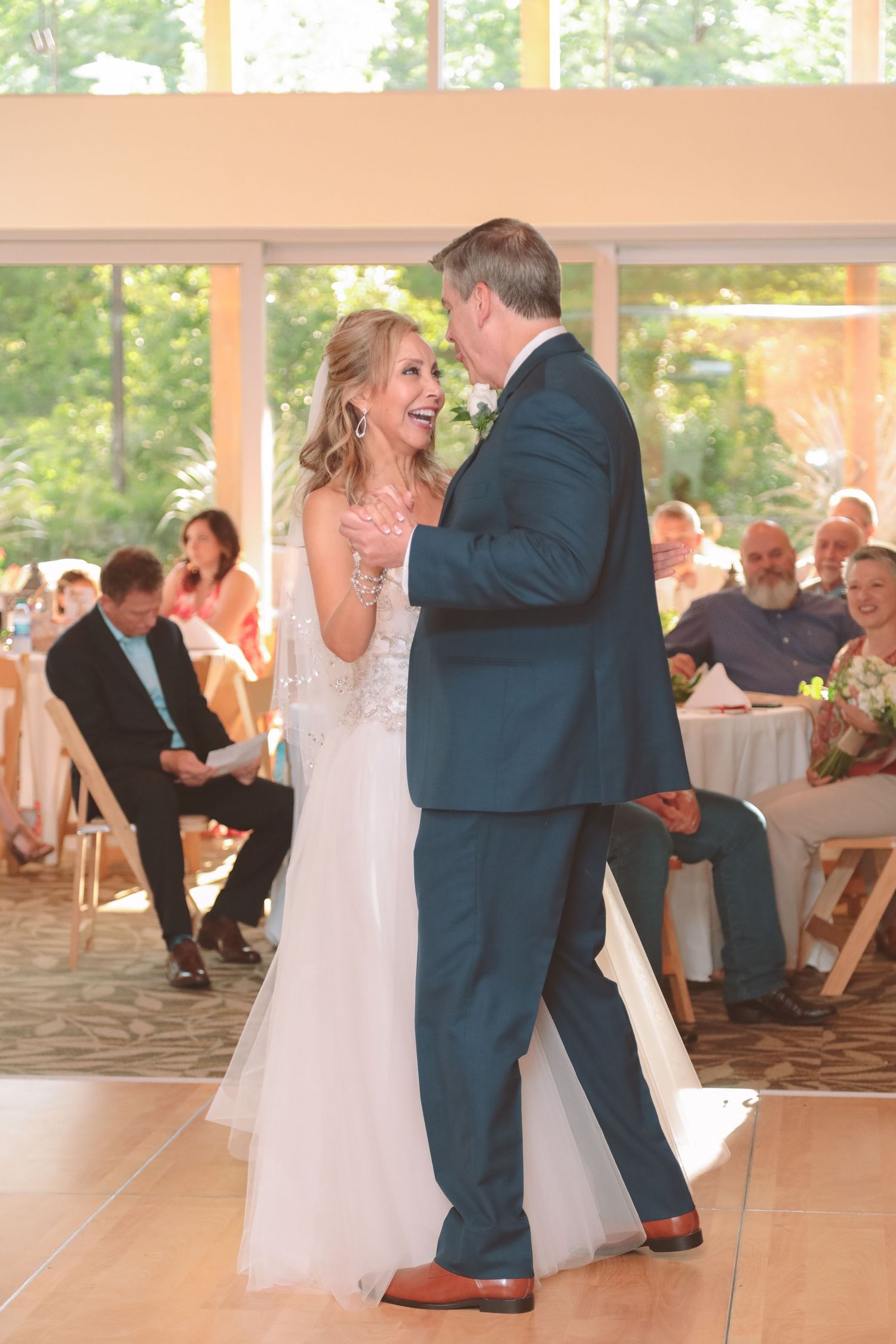 Bride and groom share joyful first dance at elegant indoor wedding reception.