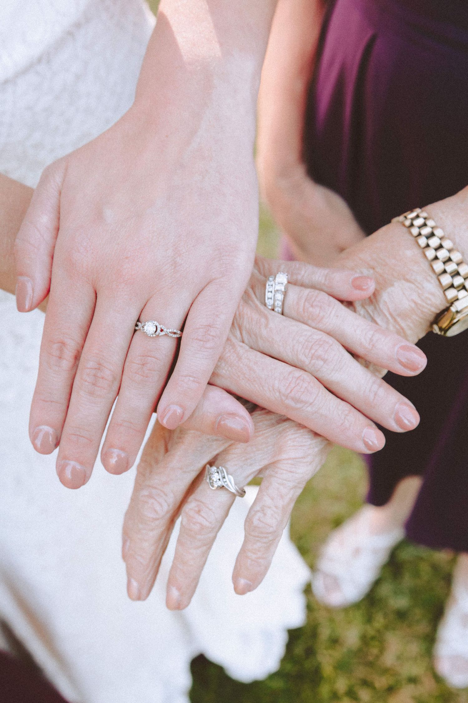 Three generations of women displaying their diamond engagement rings and wedding bands together.