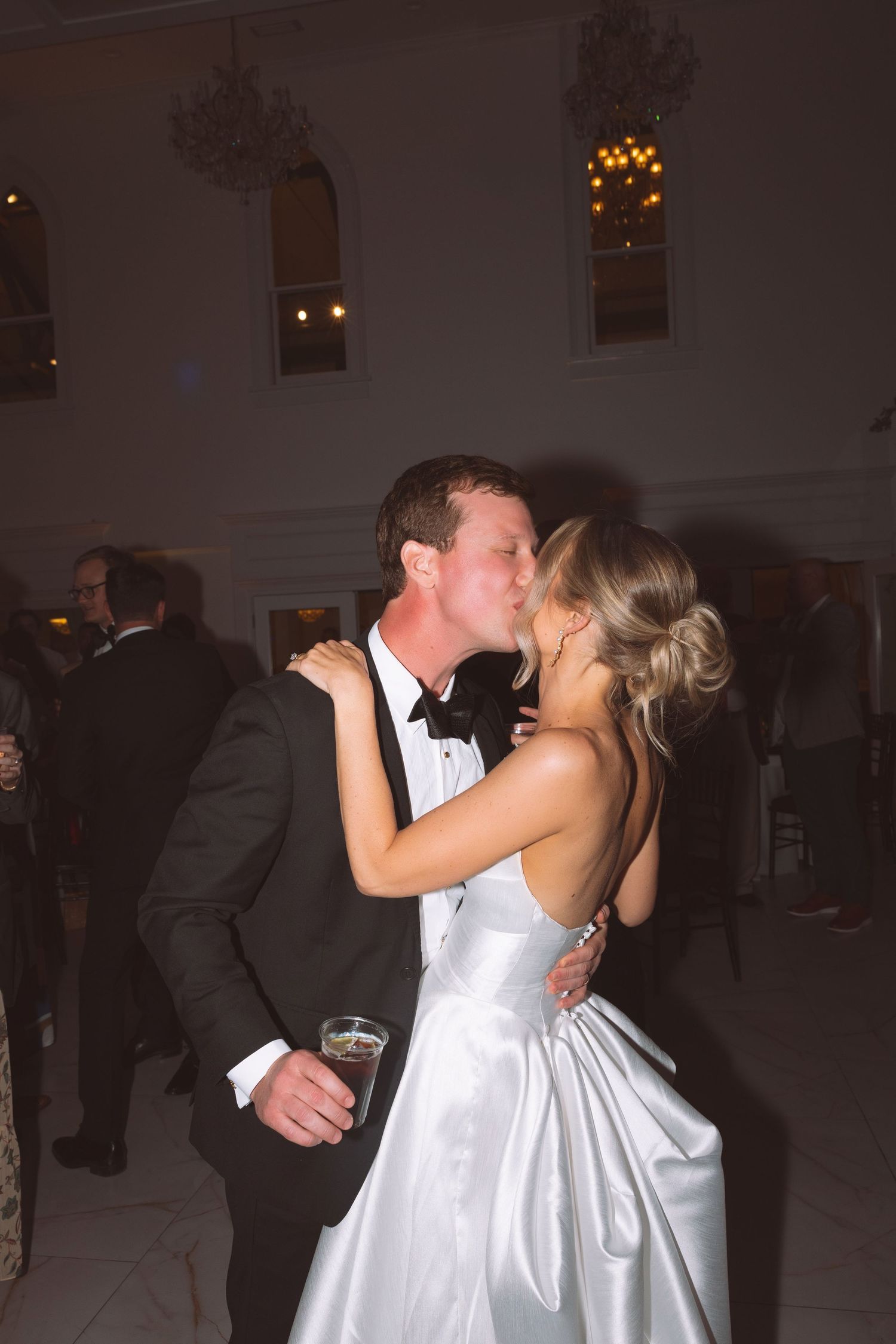 Bride and groom share a romantic kiss on the dance floor during their elegant wedding reception.