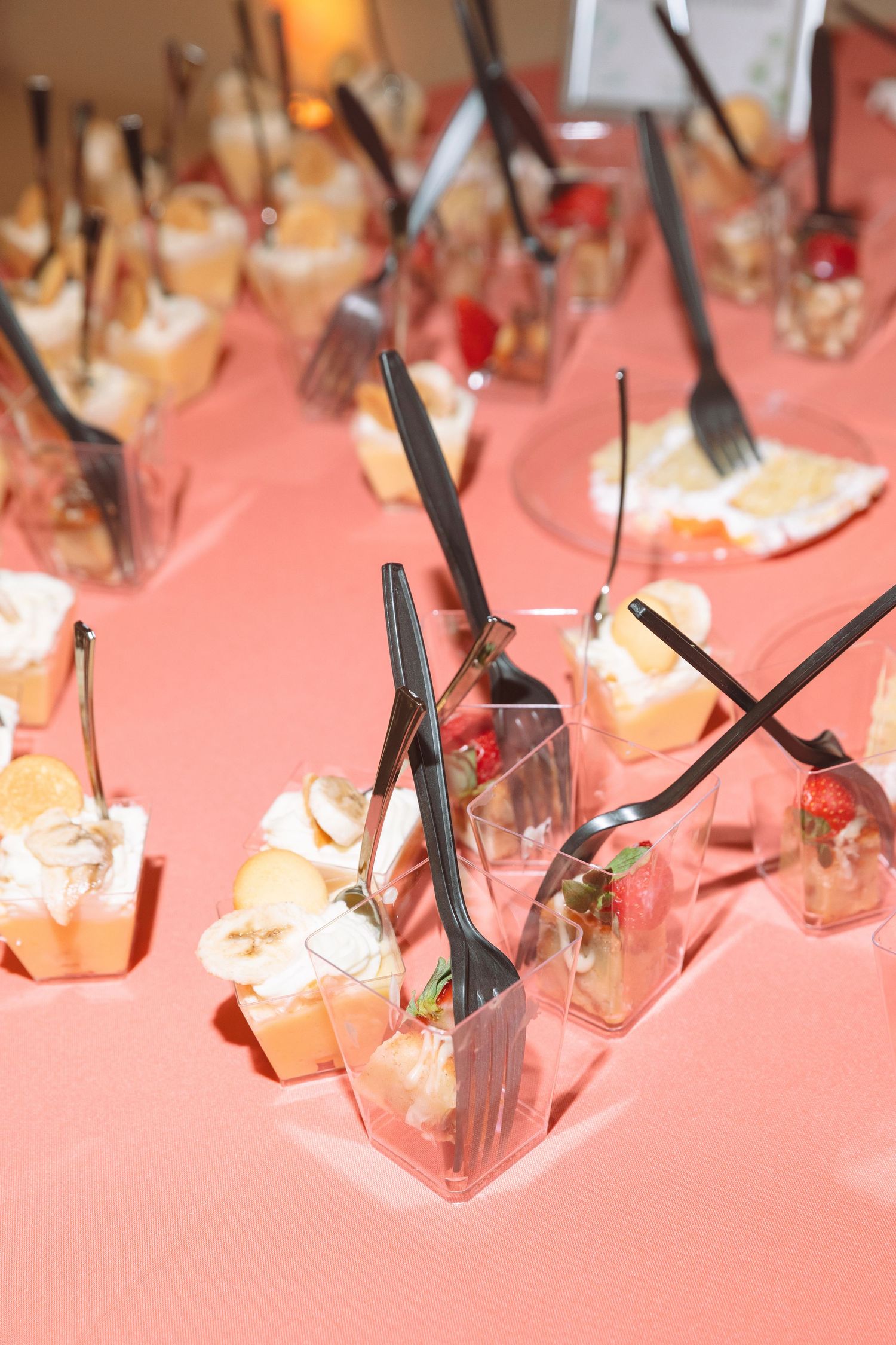 Elegant dessert table with individual fruit and cream servings in clear cups with black forks.