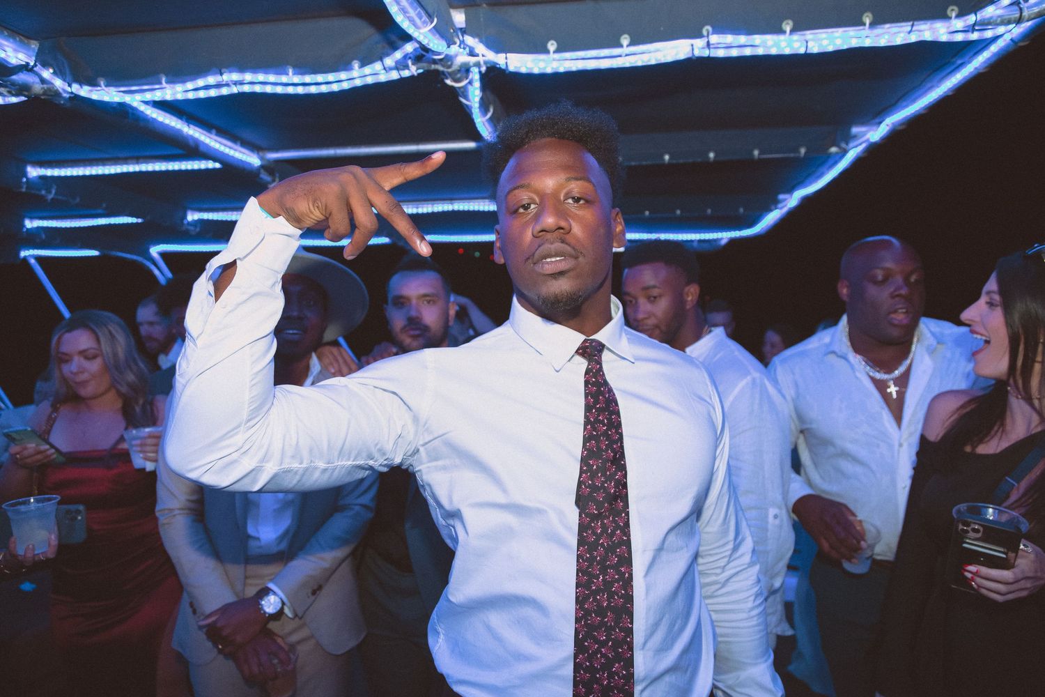 Man in white shirt and tie striking a confident dance pose at a wedding reception party.