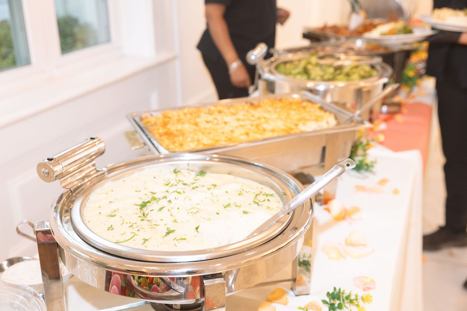 Buffet table with chafing dishes filled with hot food at a catered event.