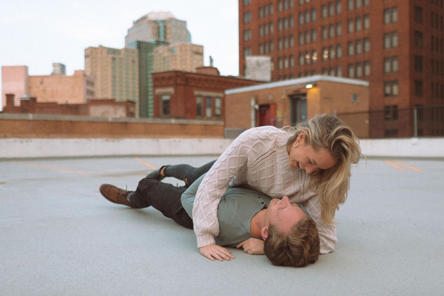 Couple sharing a romantic moment on a rooftop with city buildings in the background.