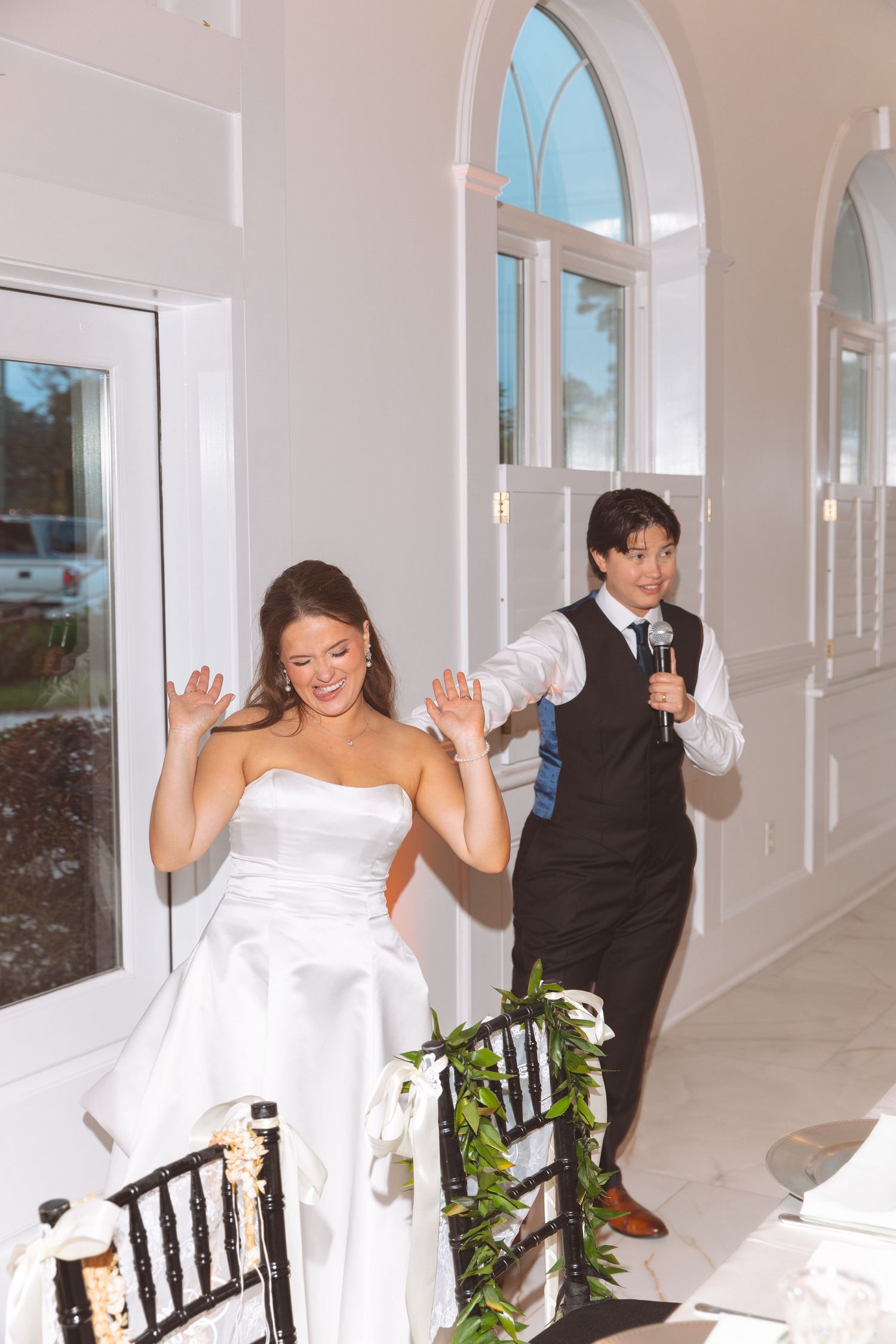 Bride and groom make a joyful grand entrance into their elegant white wedding reception venue.