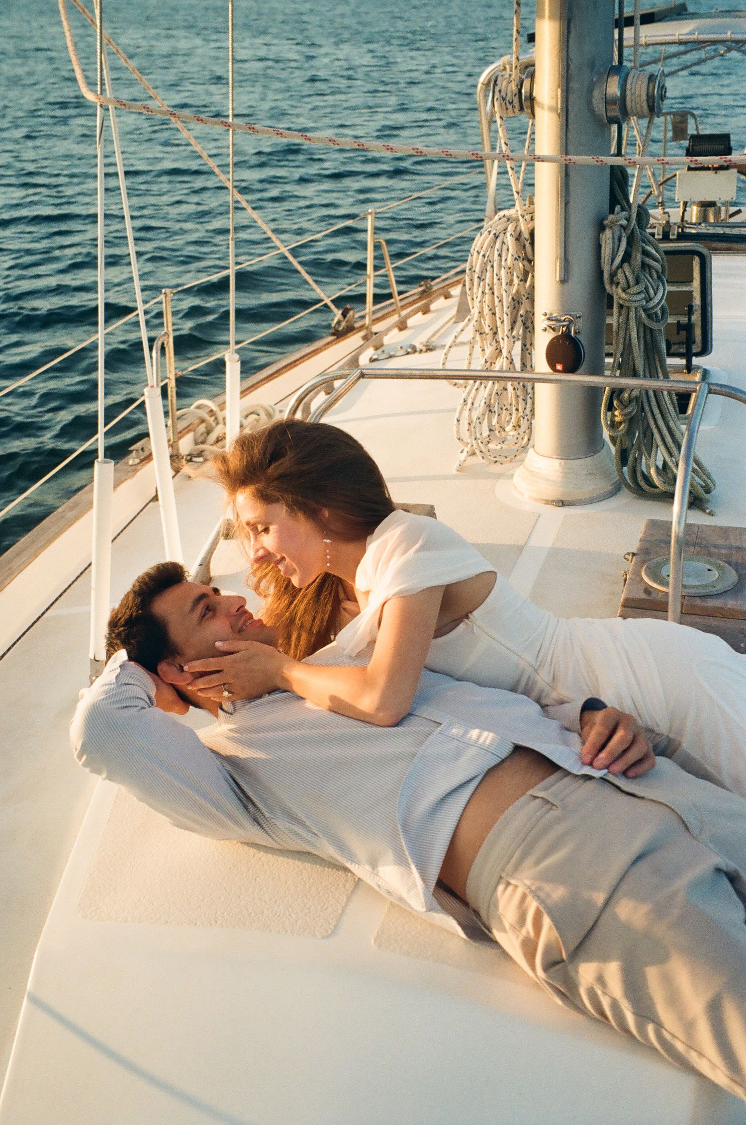 Romantic couple relaxing together on the deck of a luxury sailboat on calm ocean waters.