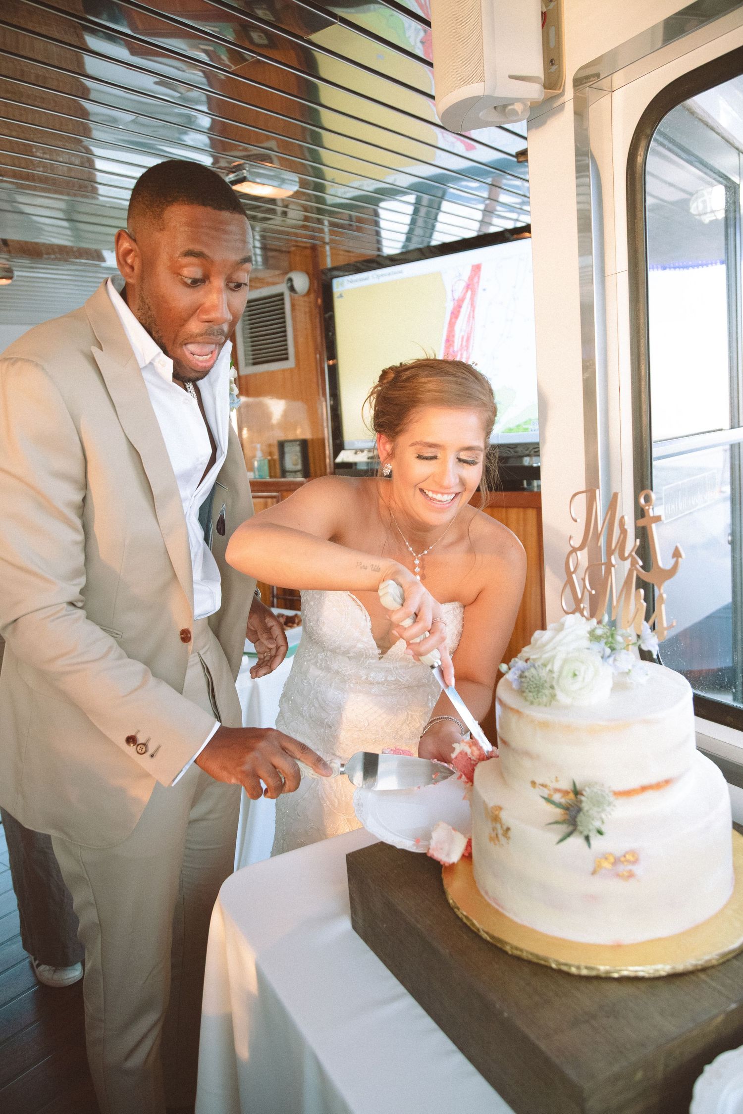 Bride and groom serving wedding cake slices together at elegant nautical boat reception venue.