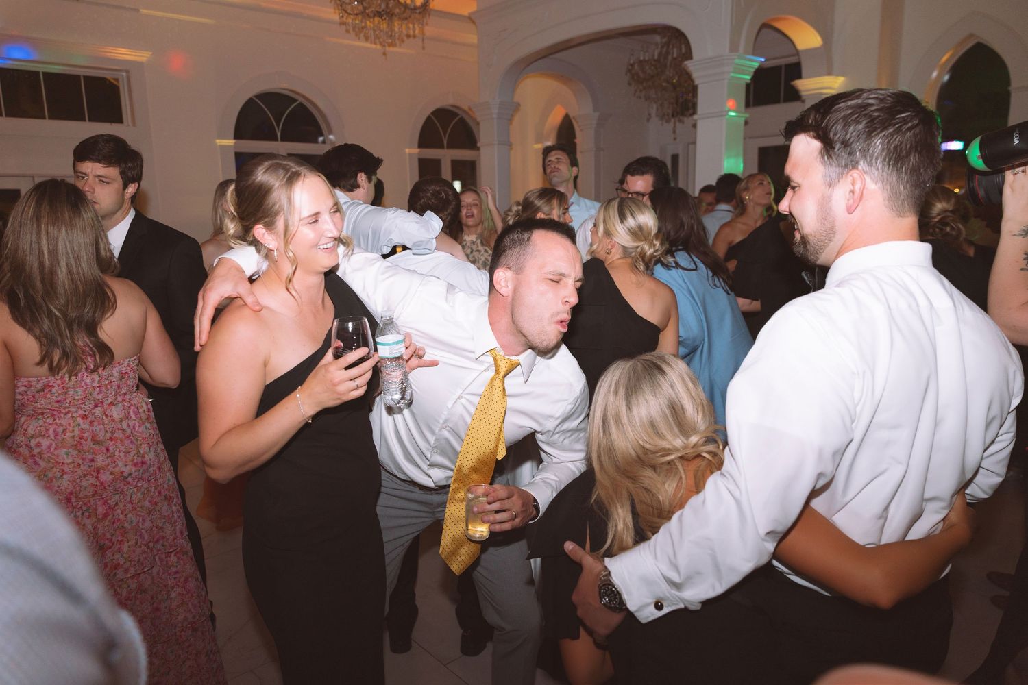Guests dance and celebrate energetically at a lively wedding reception party.