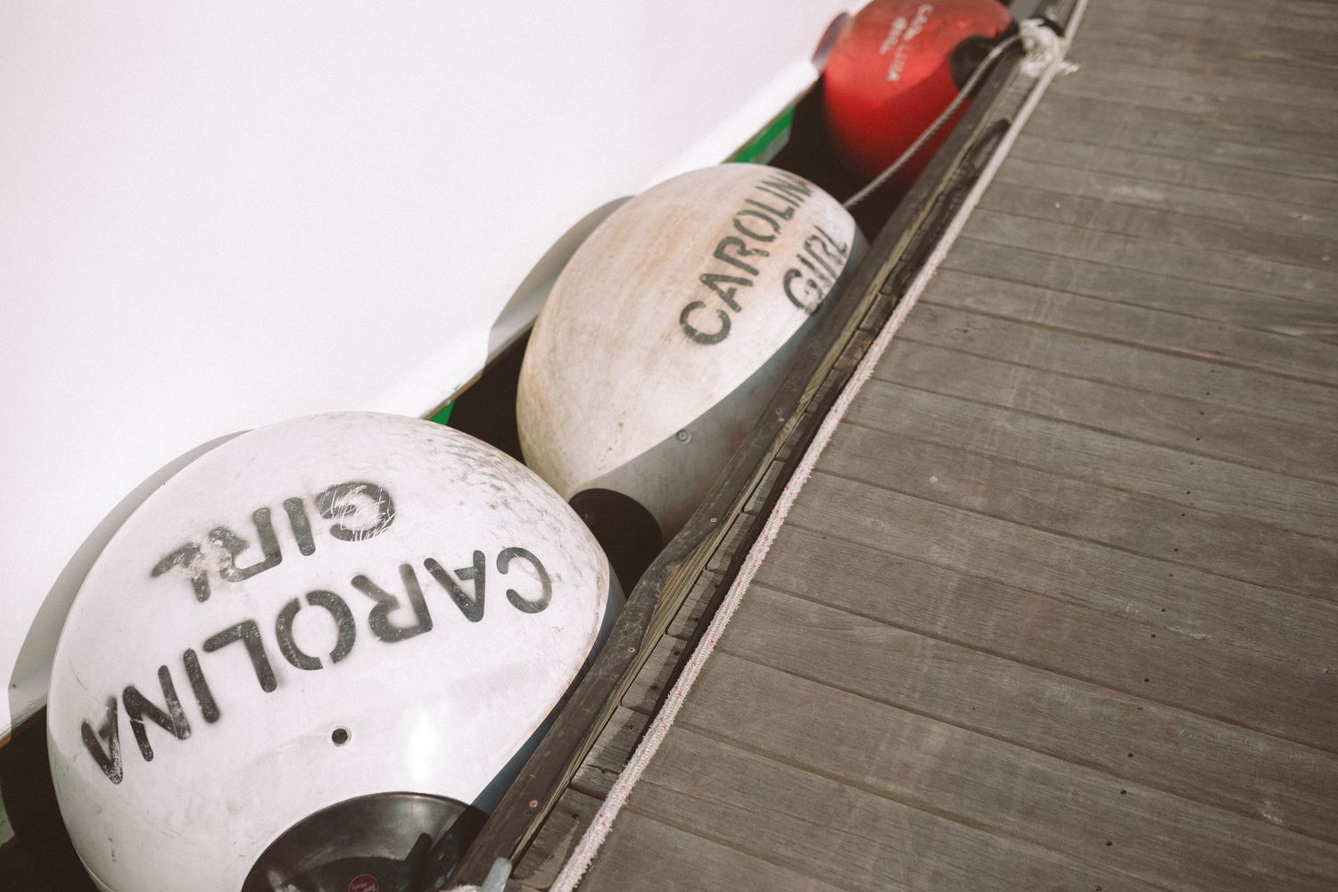 Carolina Girl boat buoys resting on a wooden dock deck in Charleston.