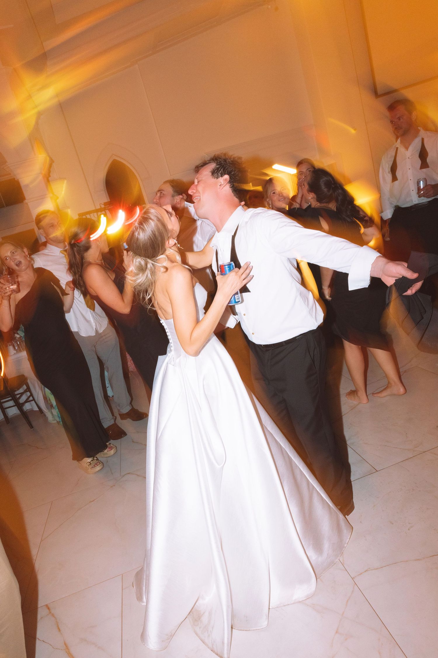 Bride and groom share a romantic first dance at their wedding reception, surrounded by guests in elegant attire.
