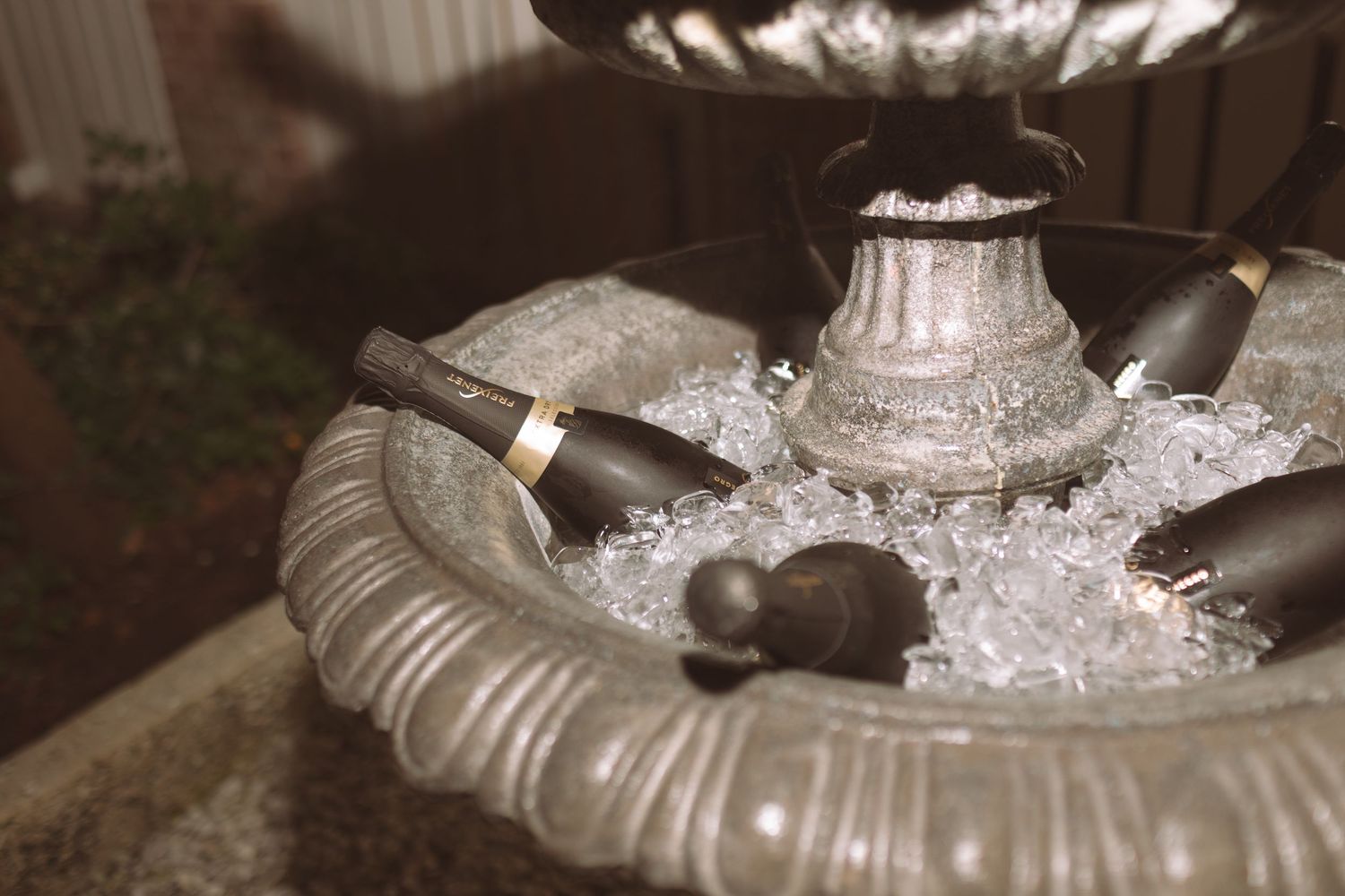 Elegant champagne bottles chilling on ice in a decorative silver fountain at a special event.
