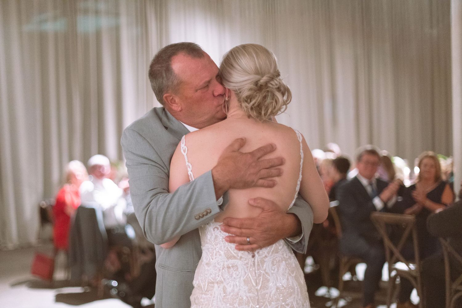 Emotional father of the bride shares a tender dance embrace with his daughter at wedding reception.