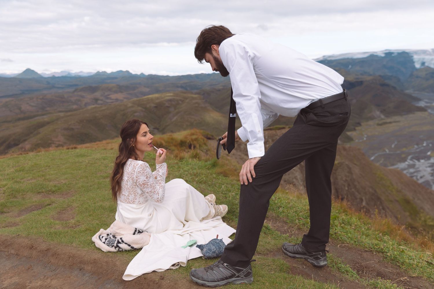 Bride and groom share a tender moment on scenic mountain hillside during outdoor wedding photography session.