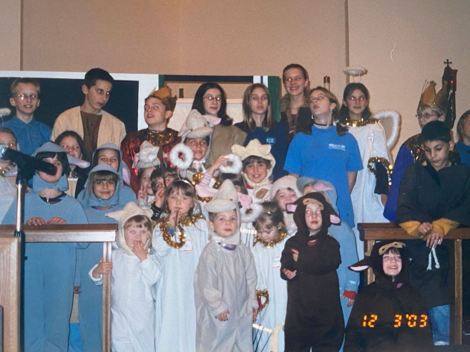 Children and adults in costumes performing a Christmas nativity play on stage.