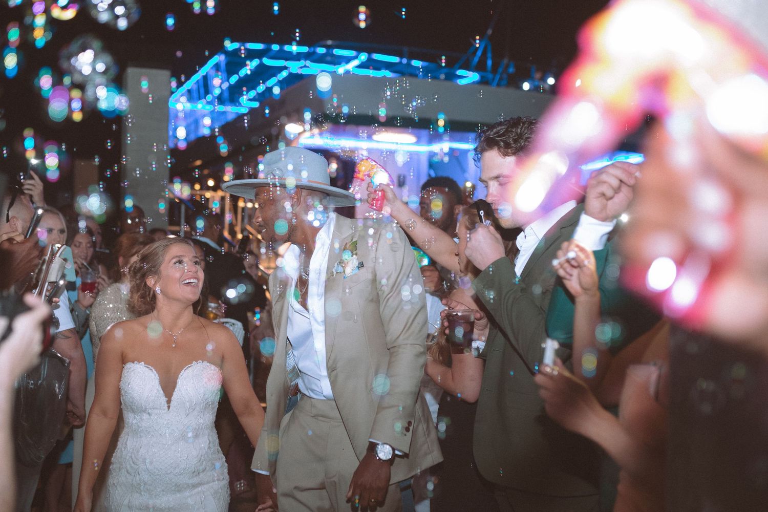 Bride and groom walk through bubble send-off at nighttime wedding celebration.