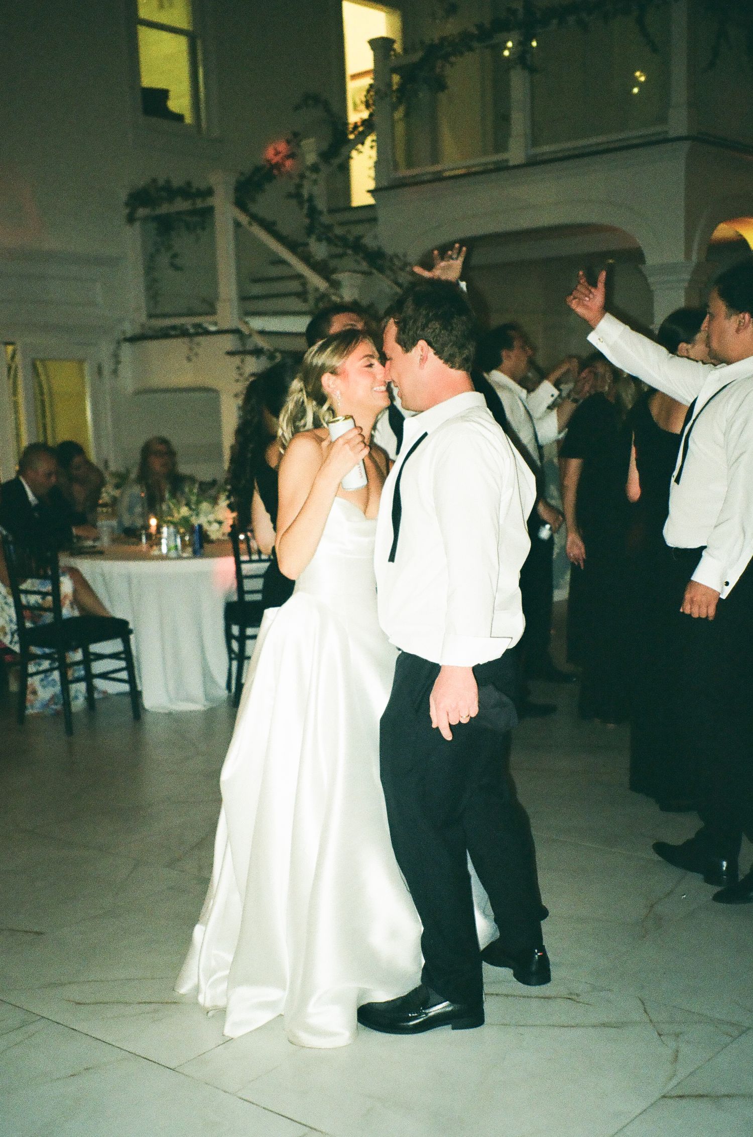Bride and groom sharing romantic kiss on dance floor at wedding reception.