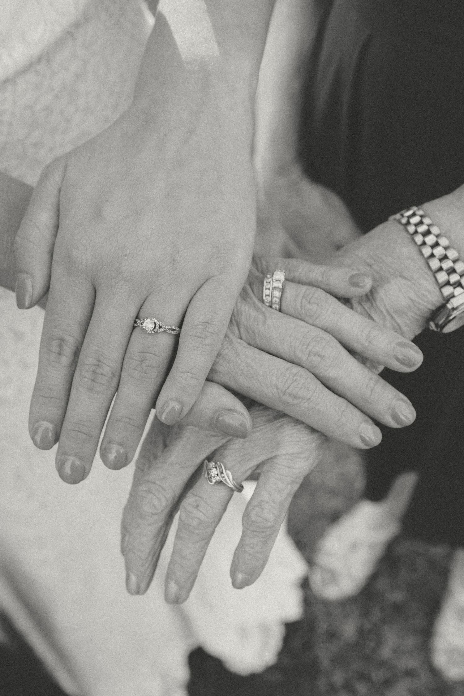 Black and white photo of three generations of women displaying diamond engagement rings and wedding bands on their hands.