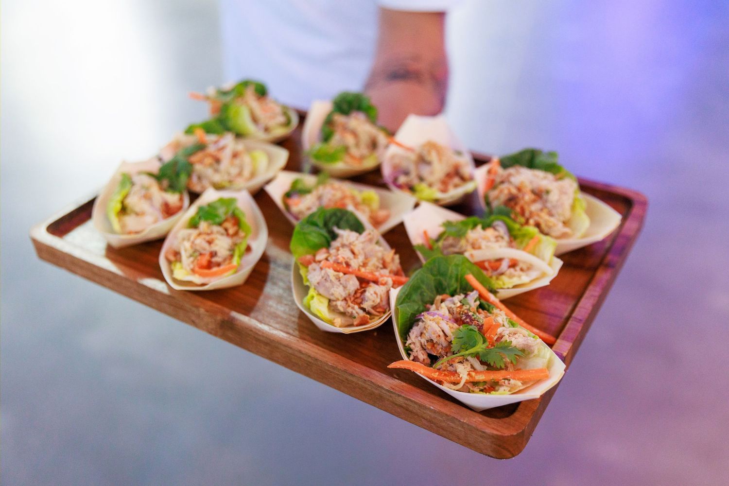 Elegant appetizers served on a wooden tray, featuring fresh lobster lettuce wraps garnished with herbs.