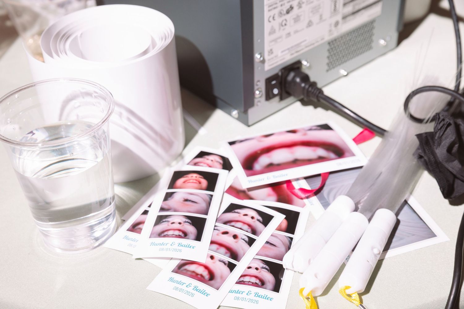 Wedding photo booth printouts and supplies arranged on a white table at a reception.