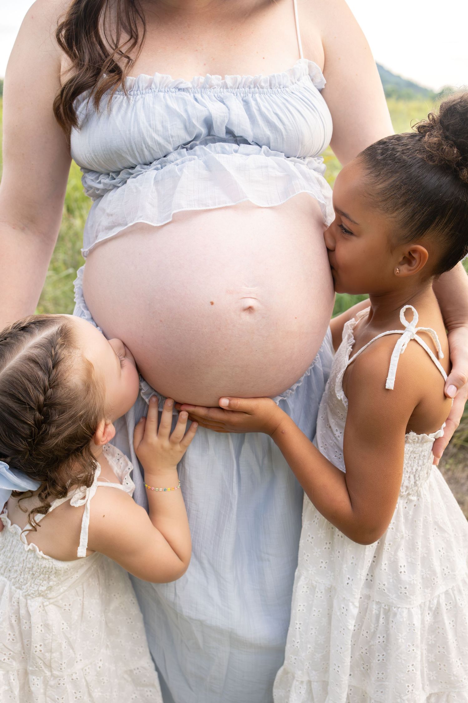 Daughters kissing mom's belly
