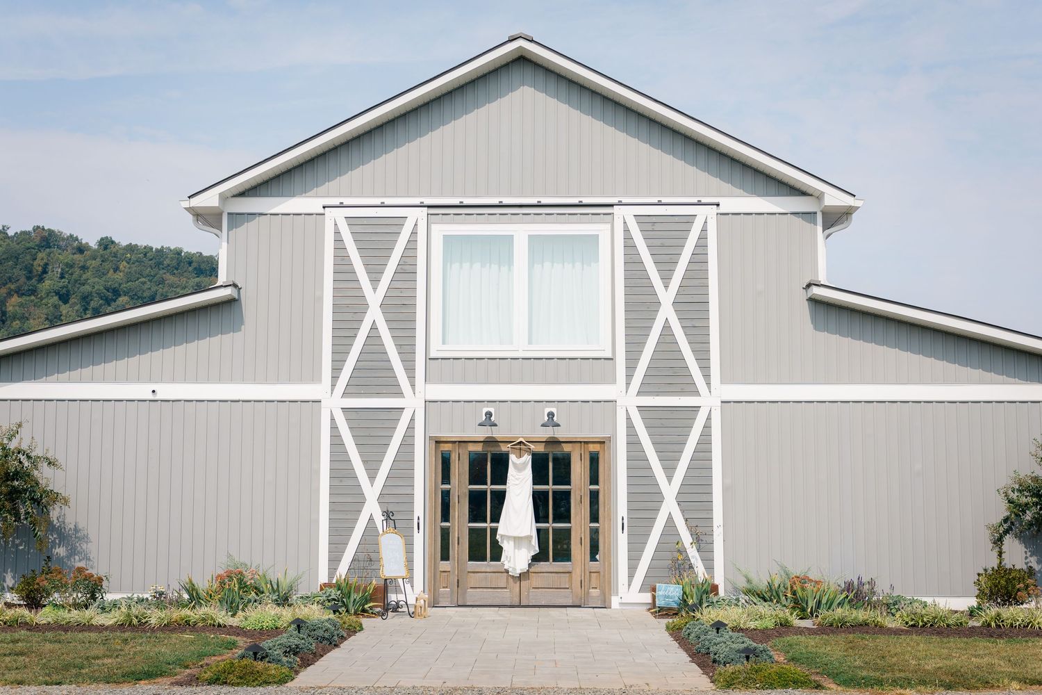 Modern white barn wedding venue exterior with symmetrical design and cross-buck details.