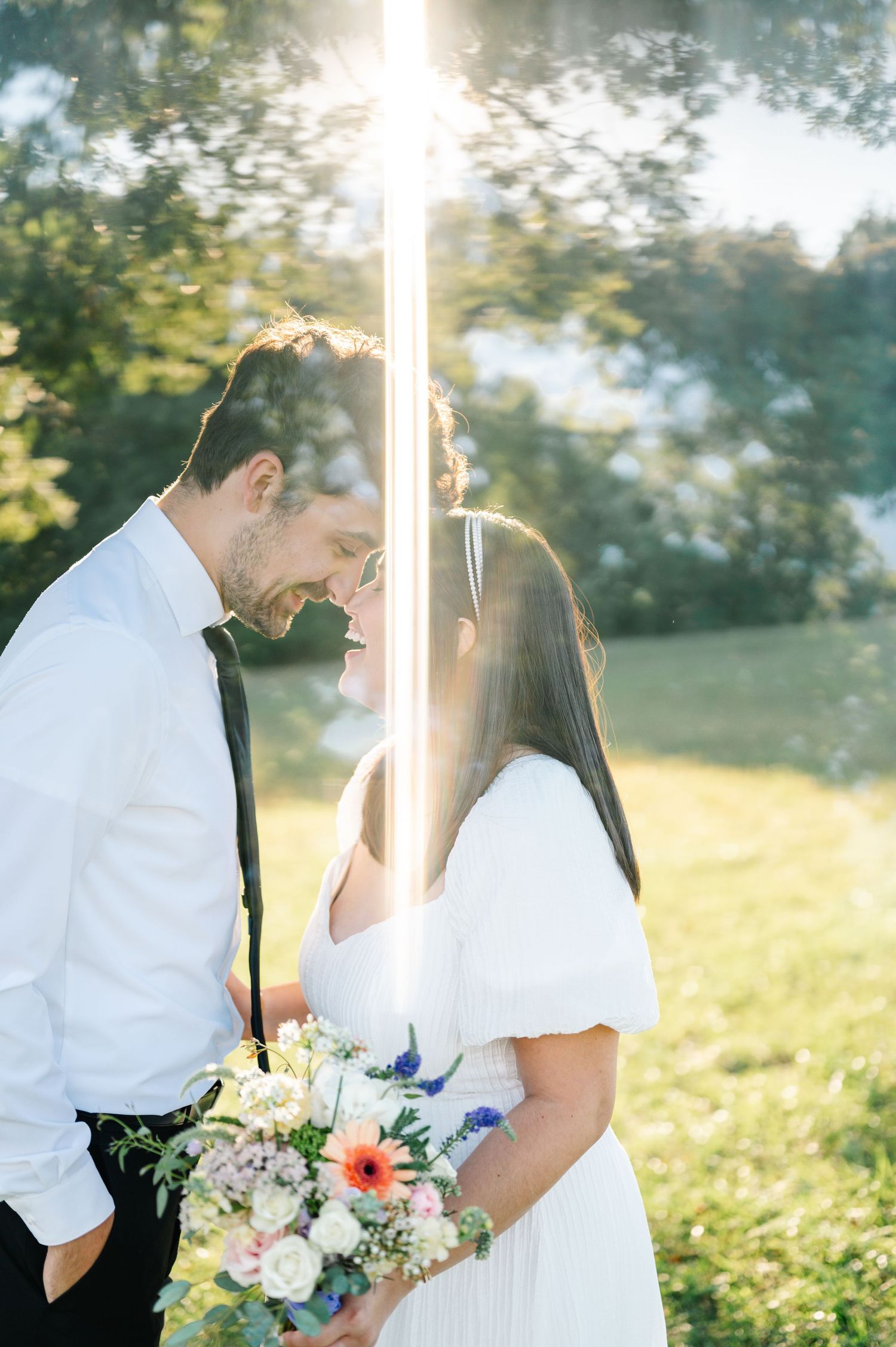 Sun-drenched outdoor couple photography session with white floral bouquet.