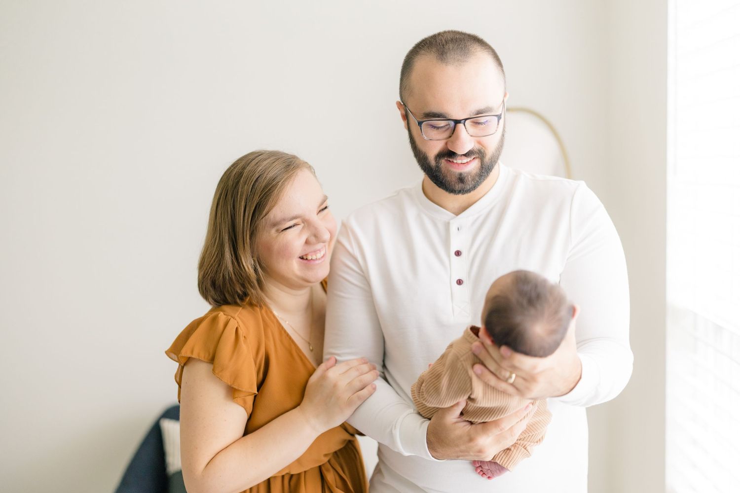Family sharing joyful moments with newborn baby in bright indoor setting.
