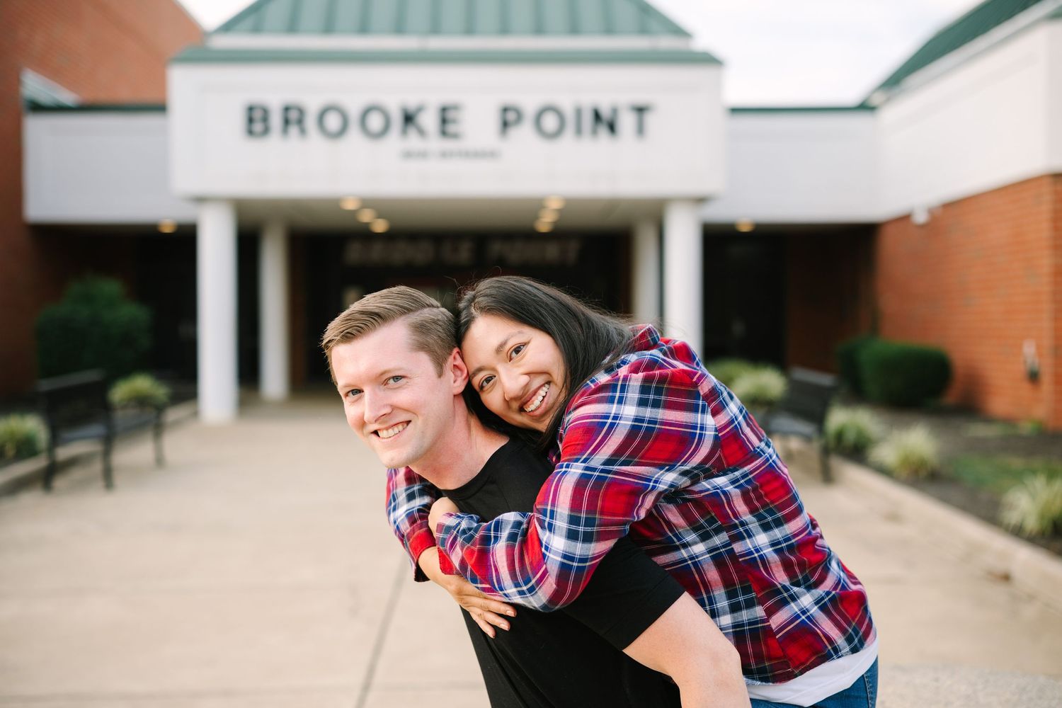Playful couple poses outside Brooke Point building entrance during photo session.