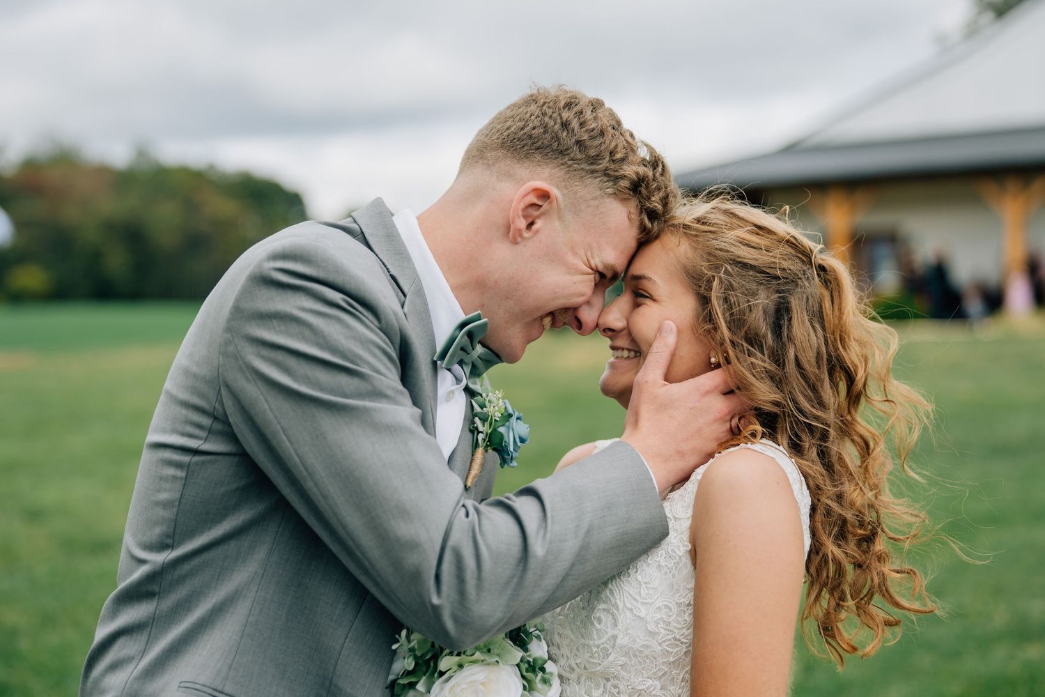 Intimate moment between couple in grey suit and white dress touching foreheads.