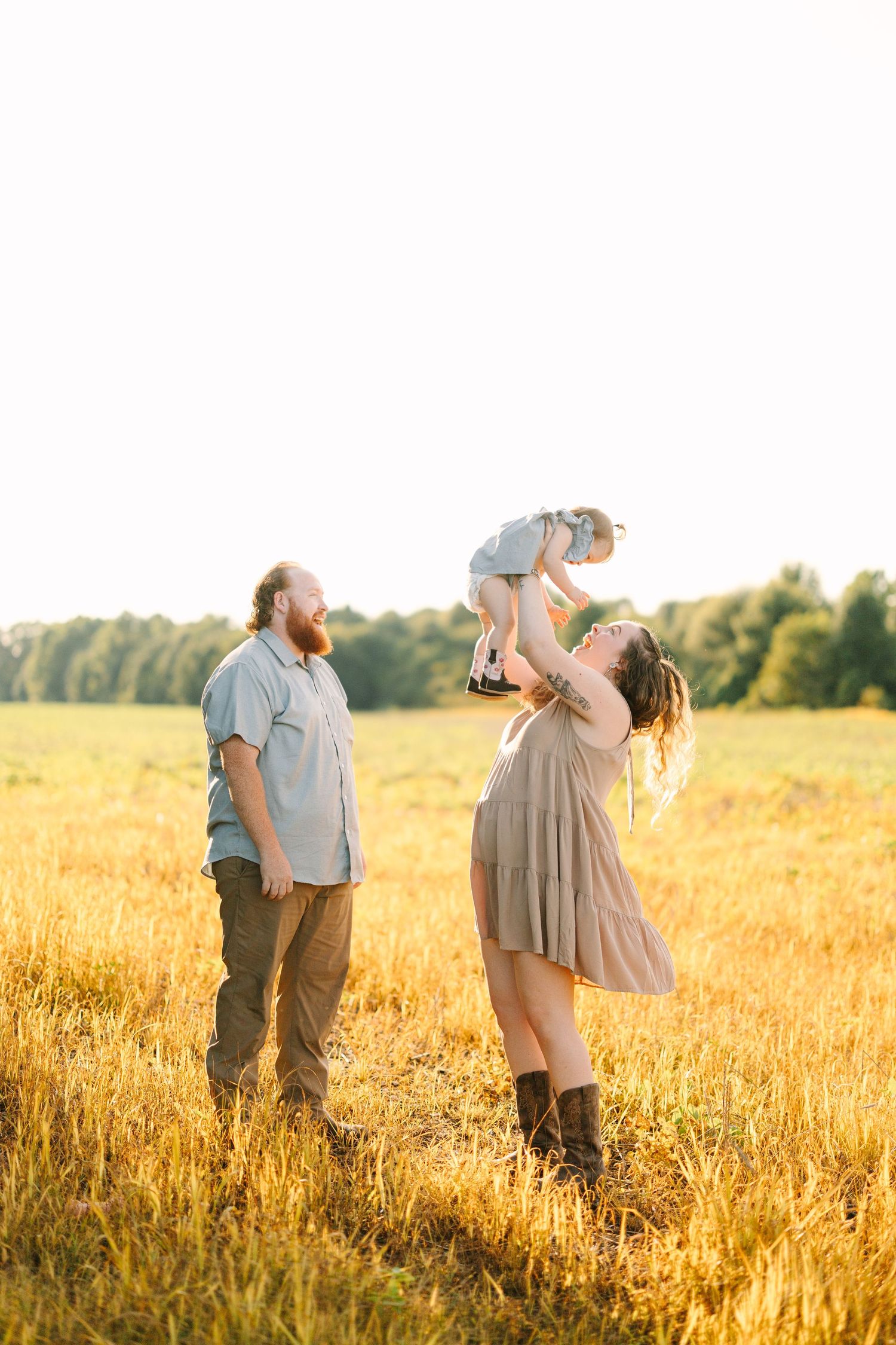 Family playing and laughing together in a golden wheat field at sunset.