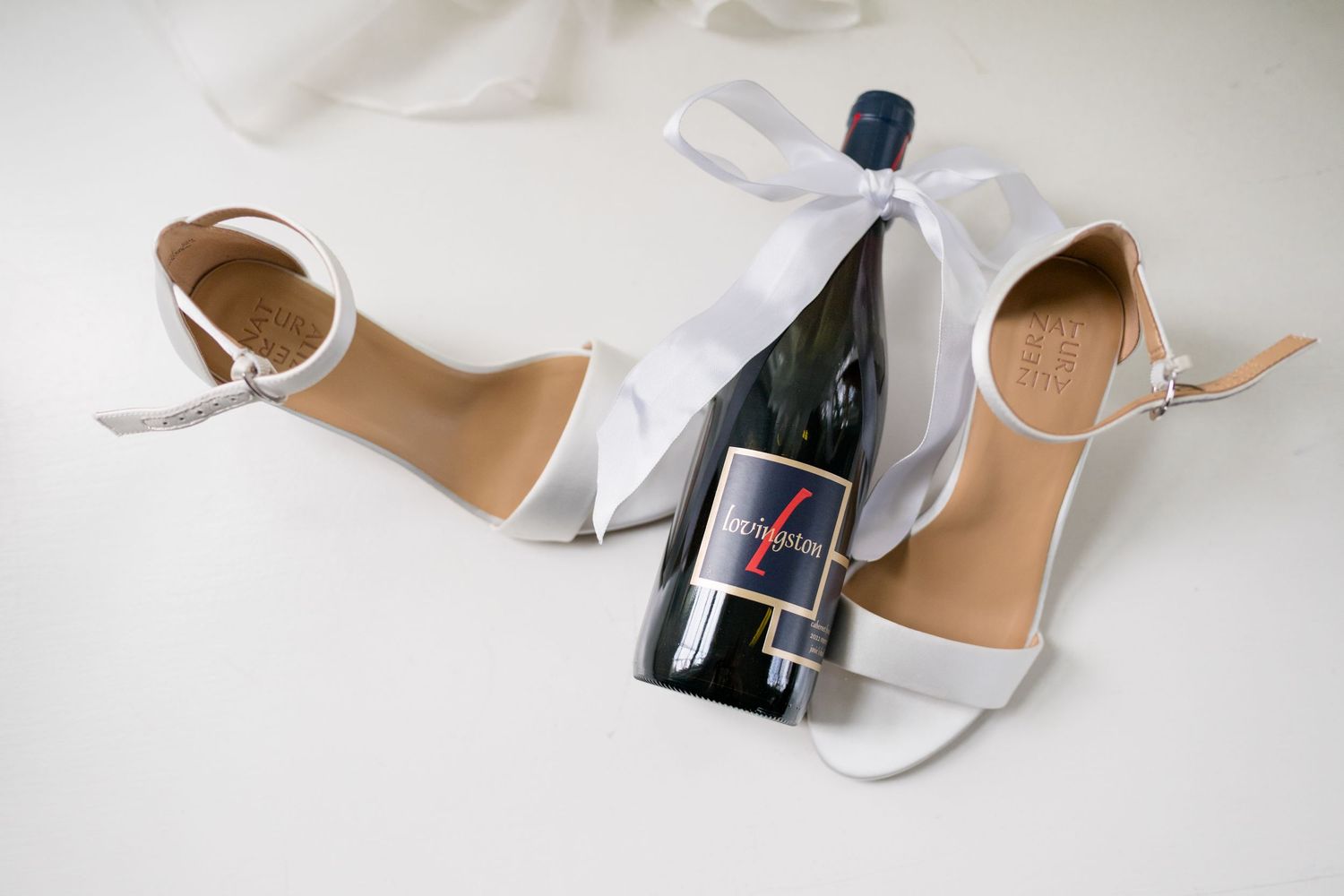 Wedding shoes and accessories arranged on white background including heels and flats.
