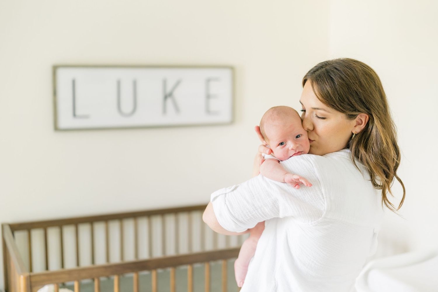 Bright lifestyle newborn photography session in modern nursery setting.