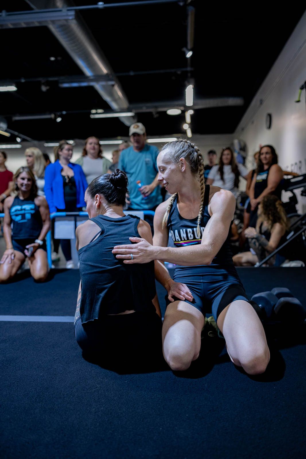 Two athletes demonstrate partner exercises during an indoor training session.