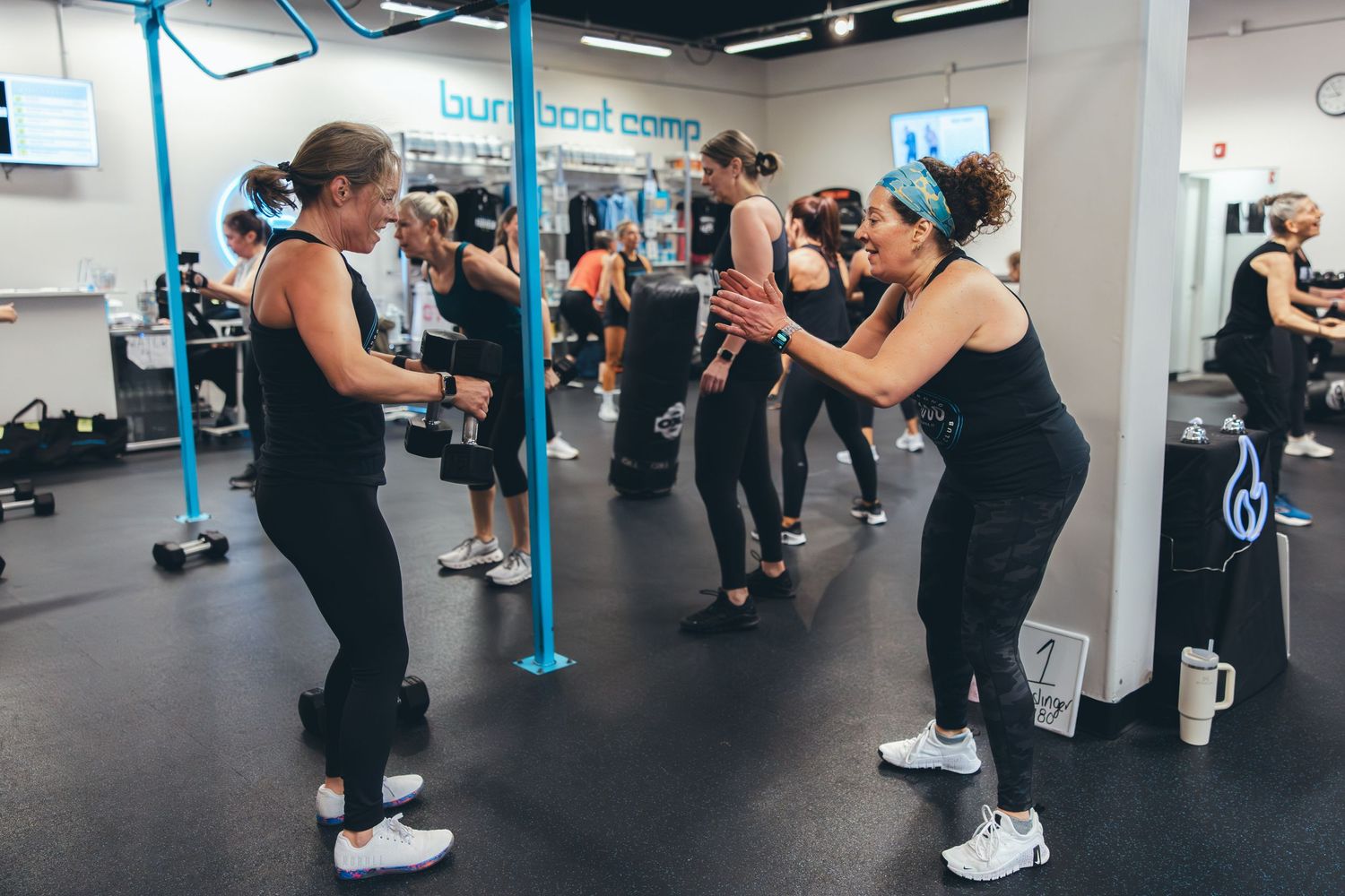 Group fitness class participants practicing boxing moves with hand weights in a modern gym studio.