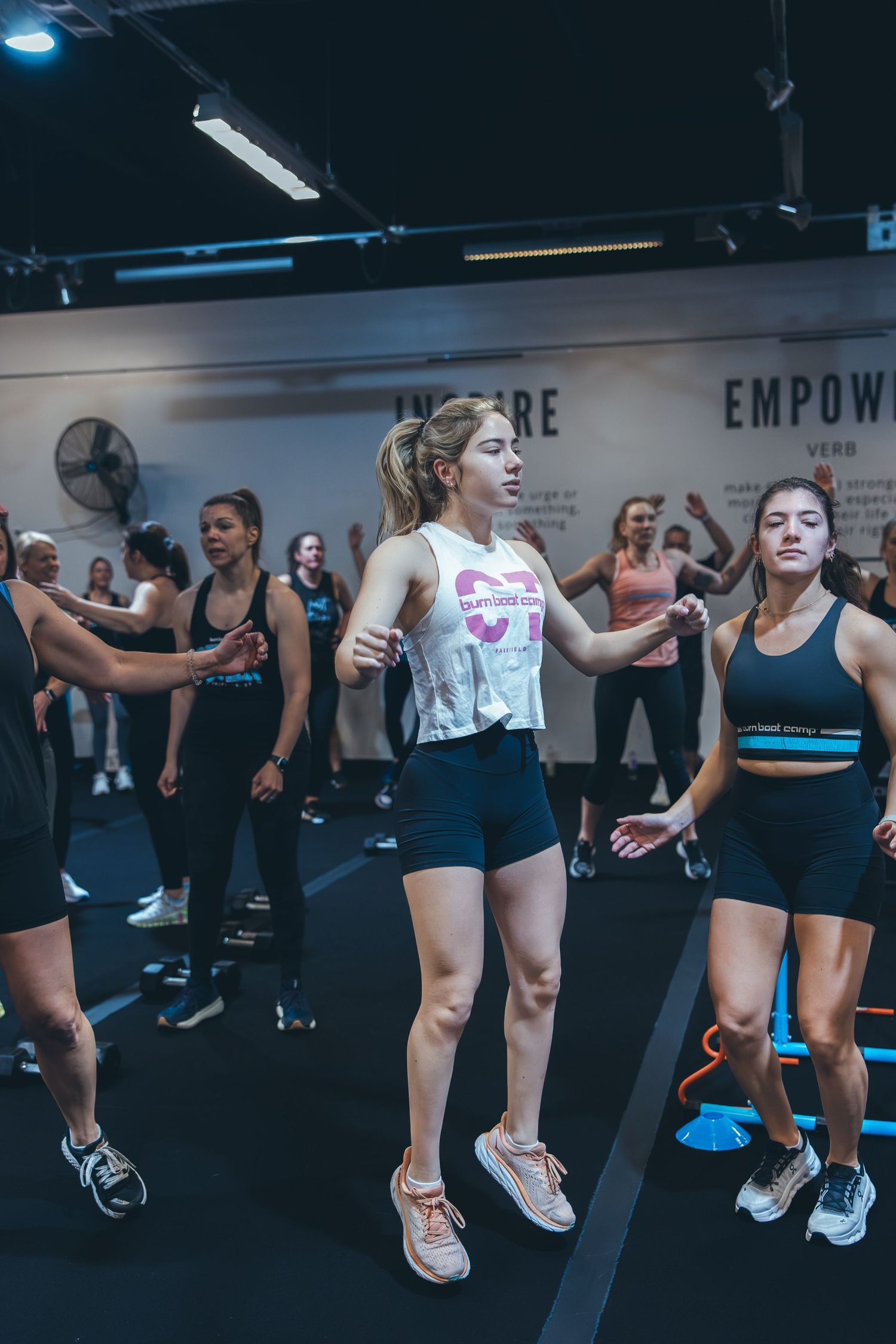 Fitness class participants jumping during high-intensity workout in modern gym setting.