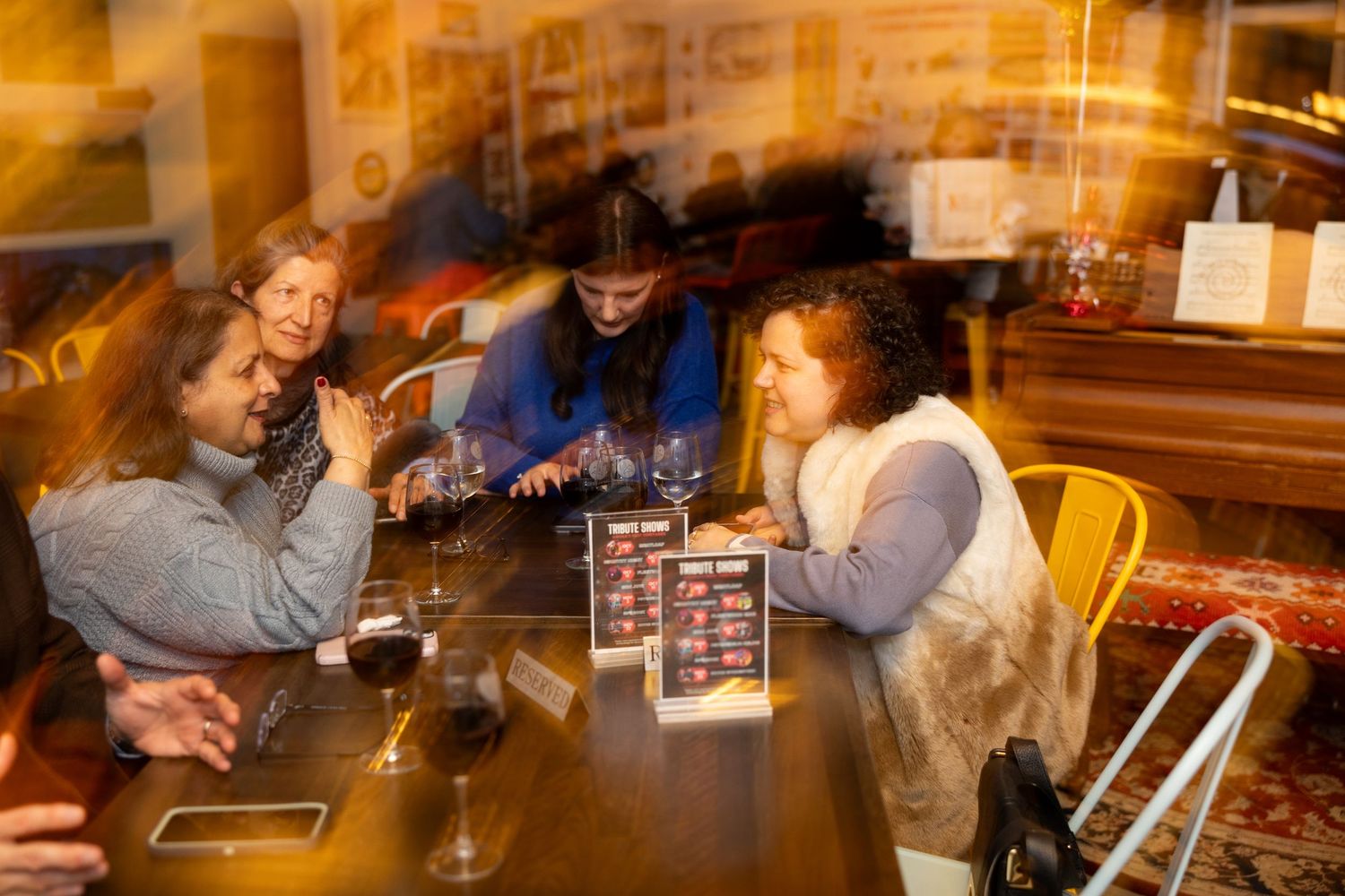People playing board games together at a cafe table with drinks and snacks in a warm, cozy atmosphere.