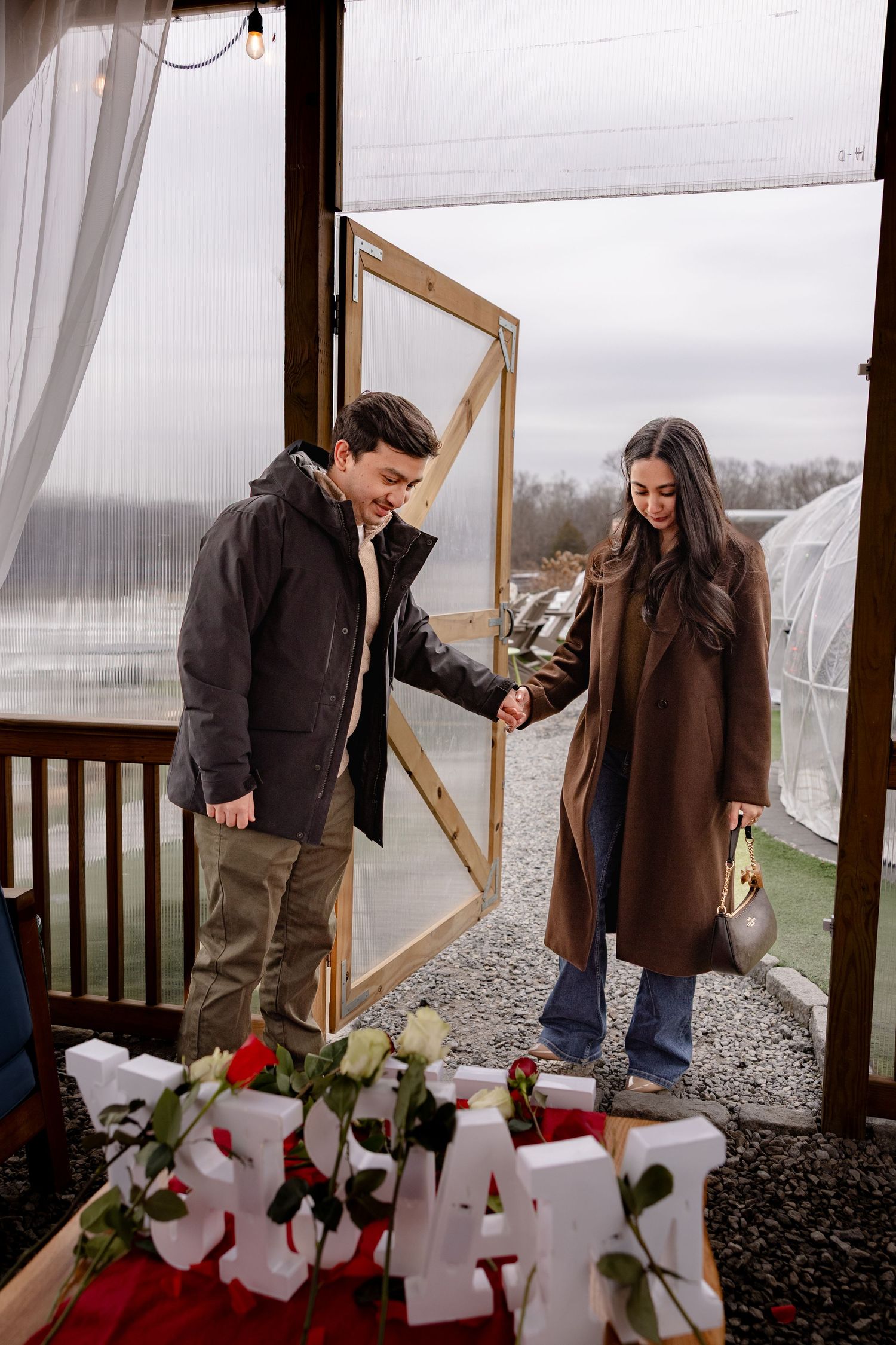 A couple places roses in a memorial display on a snowy winter day at an outdoor viewing area.