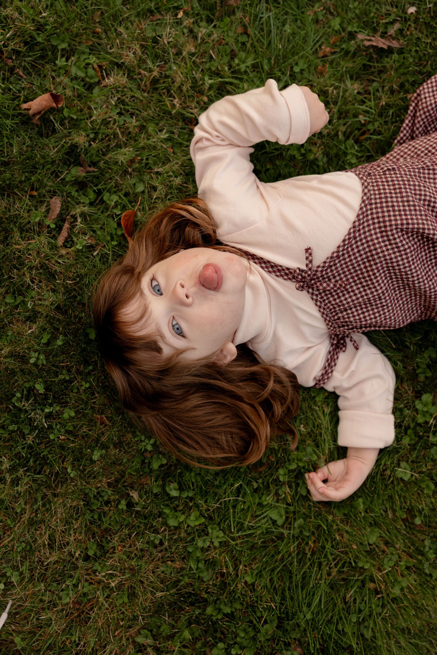 A series of photos showing someone lying in the grass wearing a white top and plaid dress during autumn.